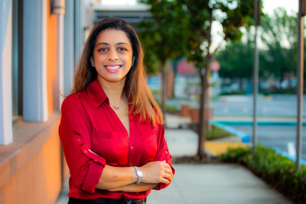 Dr. Rayani smiling with arms folded standing outside