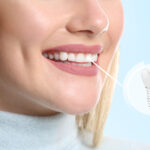 Young woman with implanted teeth on color background, closeup.